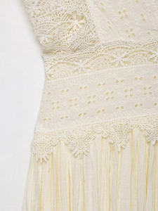 Dettaglio del ricamo in pizzo crema e del tessuto plissettato su un abito donna