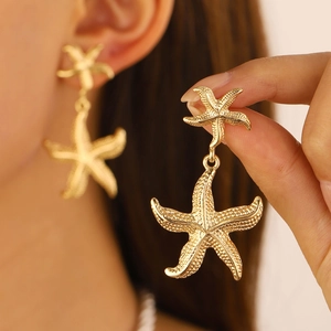 Golden starfish drop earrings with fine stippled texture in a beach vacation style