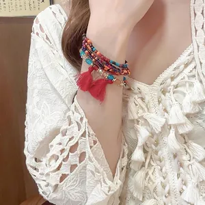 Bohemian multilayered beaded bracelet with colorful crystals and a red tassel charm