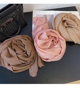 Dettaglio della trama di sciarpe a pieghe in marrone, rosa e beige con seta lucida