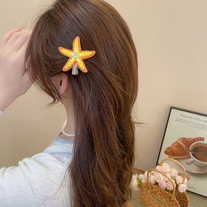 Gros plan d'une pince à cheveux étoile de mer en raphia avec strass sur les cheveux