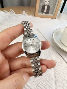 Detailed close-up of a silver stainless steel watch with a round dial and date calendar