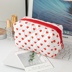 Quilted cotton heart pattern makeup bag with red zipper on a silver laptop