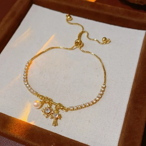 Macro view of gold bracelet featuring pearl charms, cross pendants and zircon settings