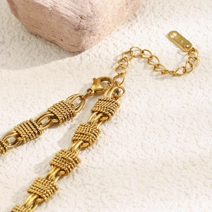 Macro detail of 18K gold plated woven texture chain with lobster clasp and K18 hallmark