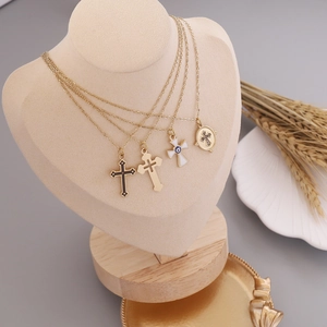 Layered gold stainless steel necklaces with evil eye and cross pendants on a mannequin