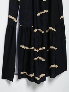 Détail d'une robe fendue française noire avec imprimé géométrique beige et volants