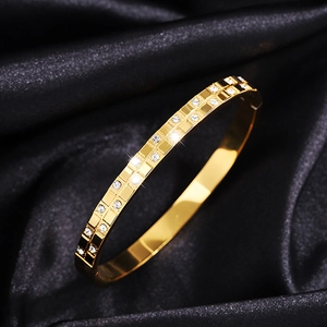 Macro shot of gold-plated waffle-style bangle with double-row diamond pavé on black silk