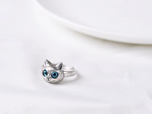 Nahaufnahme eines Vintage-Silberkatzenrings mit funkelnden blauen Edelsteinaugen und Textur