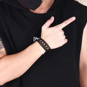 Detail of multi-layer black leather bracelet with gold beads on a male model's wrist