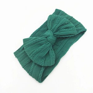 Detail of forest green cable knit baby headband with a large decorative bow