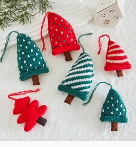 Close-up of six knitted Christmas tree ornaments with red and green patterns on snow