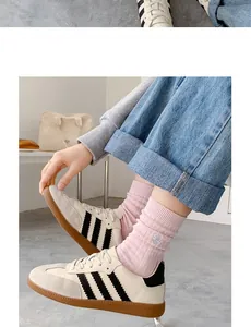 Gros plan de baskets rétro en cuir crème avec rayures noires et daim gris