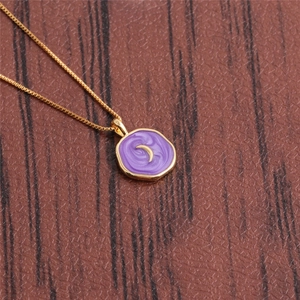Detailed close-up of a gold necklace with a purple swirl enamel moon heart pendant