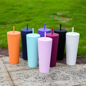Outdoor collection of colorful double-wall plastic straw tumblers with matte finish on grass