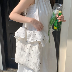 Detailed view of white canvas tote bag with floral print and ruffled chiffon edges