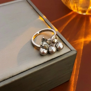 Detailed macro shot of silver ring with green gemstone, crystal and three grey pearls