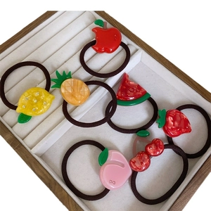Colorful acetate fruit hair ties set including watermelon and lemon designs on tray