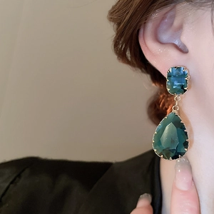 Close-up of vintage emerald green crystal drop earrings with gold textured framing