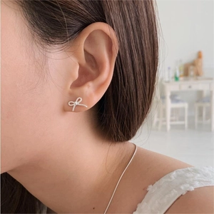 Close-up of minimalist 925 sterling silver bow earrings with detailed rope texture