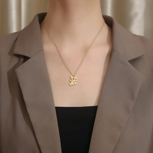 Close-up of a gold koala pendant necklace on a model wearing a brown blazer