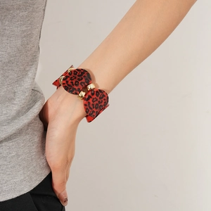 Detail of a leopard print acrylic bracelet with large oval segments and gold metal rings