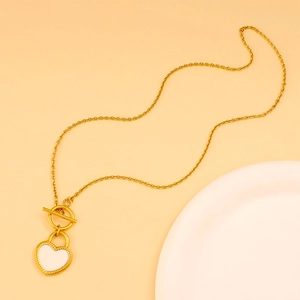 Détail macro du fermoir à bascule doré et du pendentif cœur blanc sur la chaîne