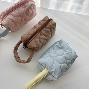 Detailed view of quilted flower texture on three pastel polyester makeup bags with handles