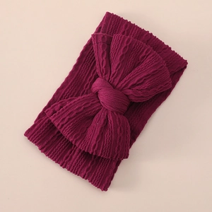 Detail of burgundy ribbed knit baby headband featuring a soft oversized texture bow