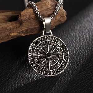 Detail of silver compass pendant necklace with black gemstone on rustic wood surface