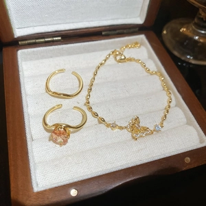 Close-up of 18k gold plated butterfly bracelet and zircon rings in a wooden jewelry box
