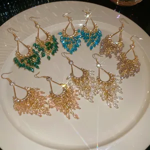 Elegant bohemian teardrop crystal tassel hook earrings in multiple colors on a ceramic plate