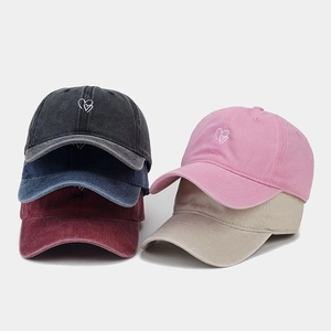 Détail montrant plusieurs couleurs de casquettes en coton délavé avec broderie cœur