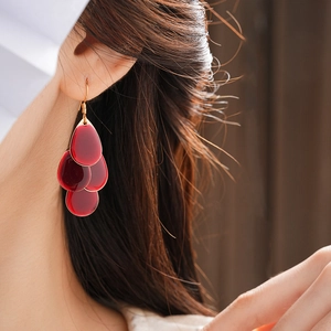 Close-up of burgundy tiered water-drop earrings with gold hooks on model ear