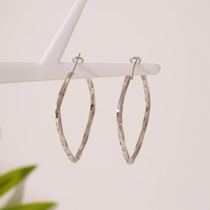 Minimalist silver twisted geometric hoop earrings displayed on a white jewelry stand
