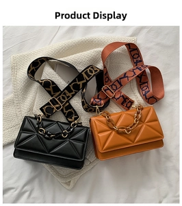 Detail view of black and caramel crossbody bags with chain handle and wide fabric strap