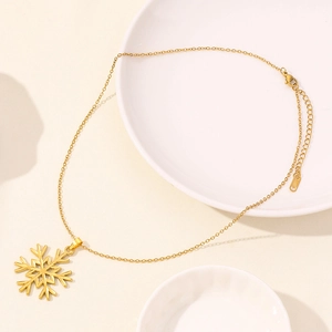Detailed view of a gold snowflake pendant necklace on a minimalist ceramic dish