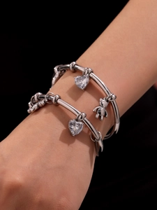 Close-up of layered silver bear and heart zircon pendants on bracelets for women