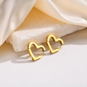 Detailed view of glossy heart-shaped gold hoop earrings on elegant silk and stone