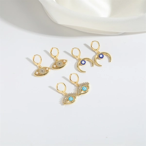 Golden Evil Eye and crescent moon earring set with rhinestones and pearls on white satin