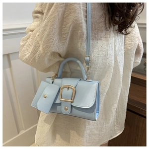 Detail of light blue crossbody bag with gold buckle and mini pouch shown on model