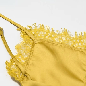 Detail of mustard yellow satin midi dress featuring delicate lace trim and silk texture