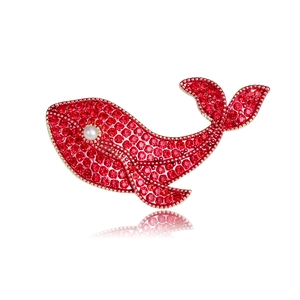 Détail macro de la broche baleine avec cristaux rouges, base dorée et perle blanche