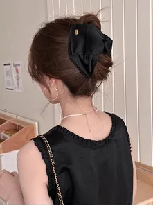 Pince à cheveux noeud en satin noir de style français avec détail de badge doré