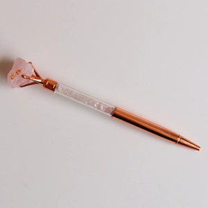 Detail of rose gold metal pen with pink crystal raw stone and crushed gem filling