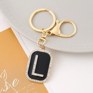 Close-up of black rhinestone-encrusted letter L keychain with golden lobster clasp