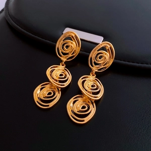 Detailed close-up of golden spiral drop earrings on a premium black leather texture