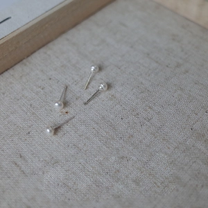 Macro detail of minimalist 925 silver pearl earrings on a textured linen background