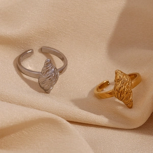 Close-up of gold and silver seashell rings with textured details on beige fabric