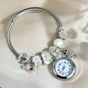 Detail of silver beaded bracelet watch with pink floral and rhinestone crown charms